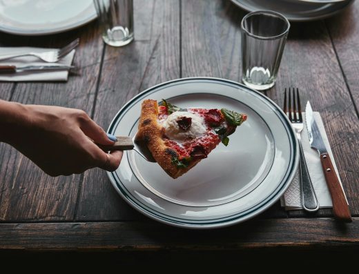 cropped shot of woman serving slice of pizza margherita on plate at restaurant