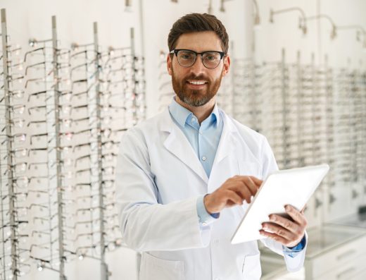 Male optician with digital tablet on background of shop windows with different models of glasses